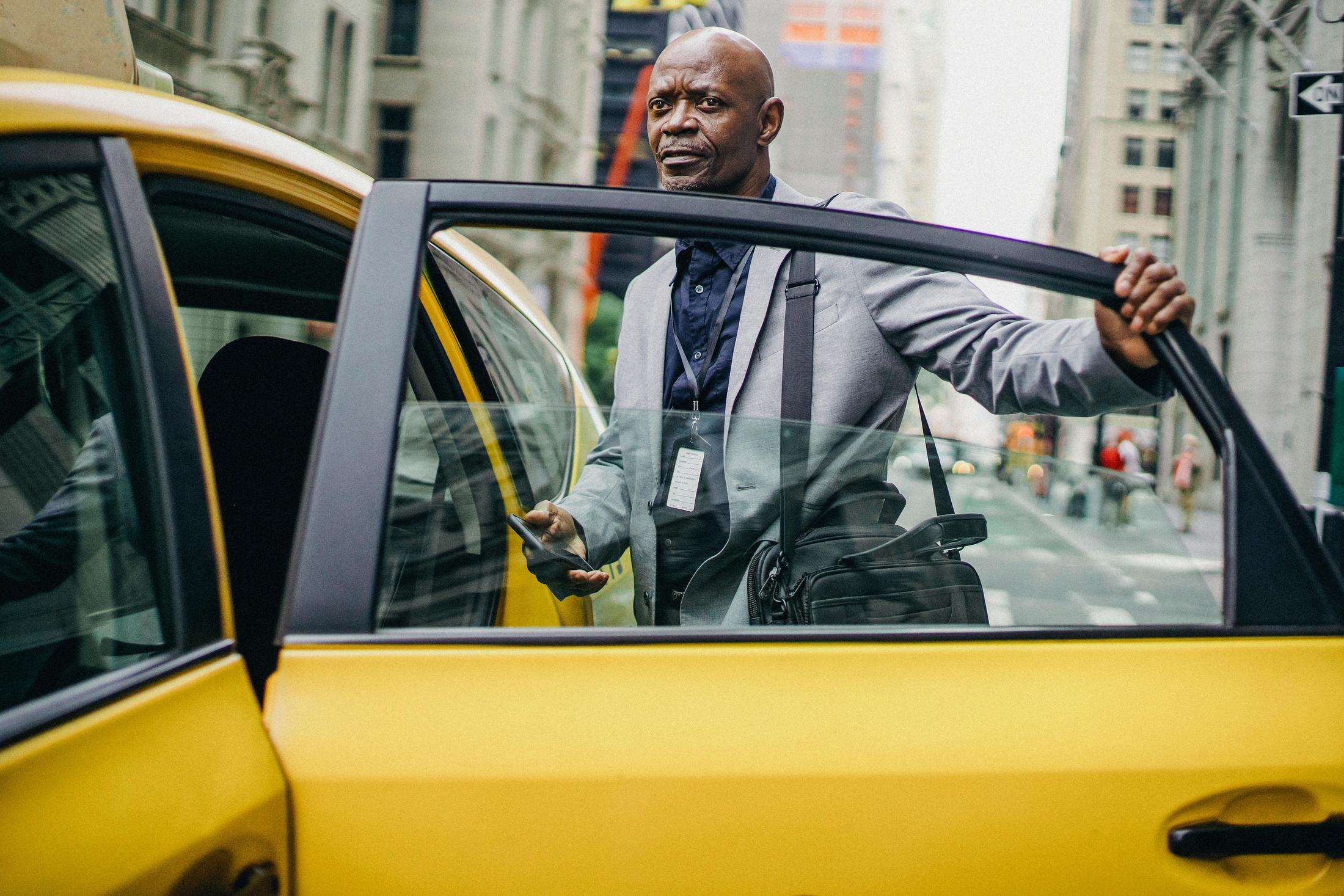 Business traveler opening a taxi door for a Handei corporate transport pickup.