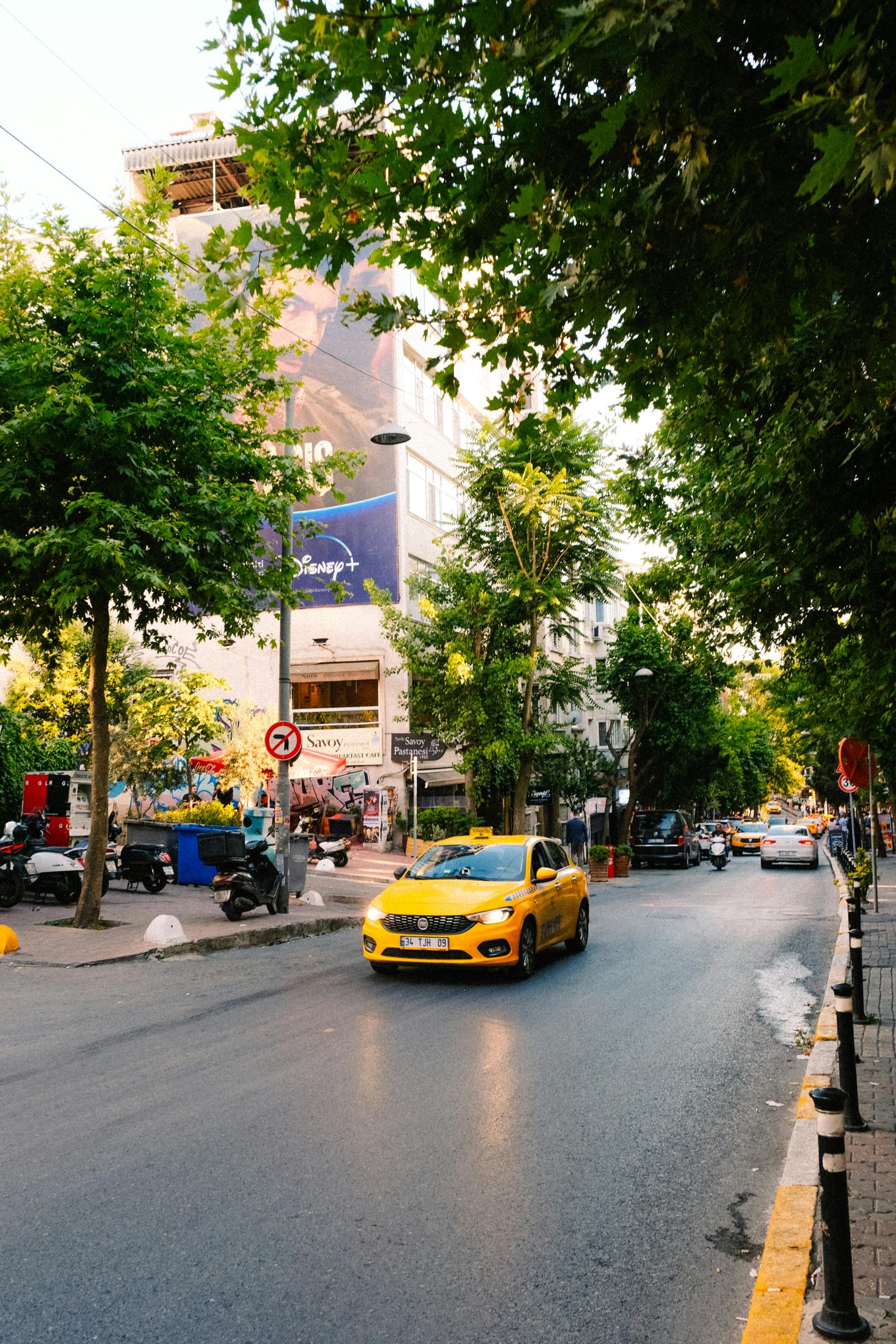 Yellow taxi driving through a leafy city street for a Handei holiday tour.